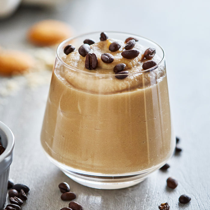 Soft serve ice cream in a dish, topped with whole coffee beans, alongside the Frost Classic recipe book.