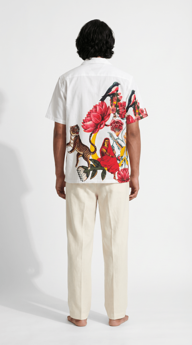 Man wearing the white 16 Bit Retro Art shirt with cream trousers, back view