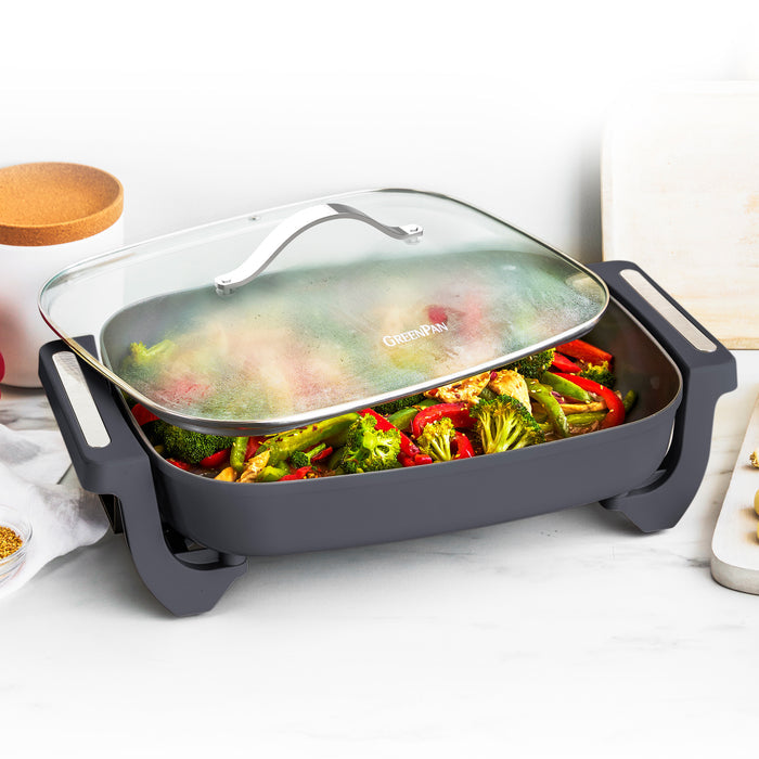 Graphite 7-quart skillet with cooked broccoli and red peppers resting on a countertop.