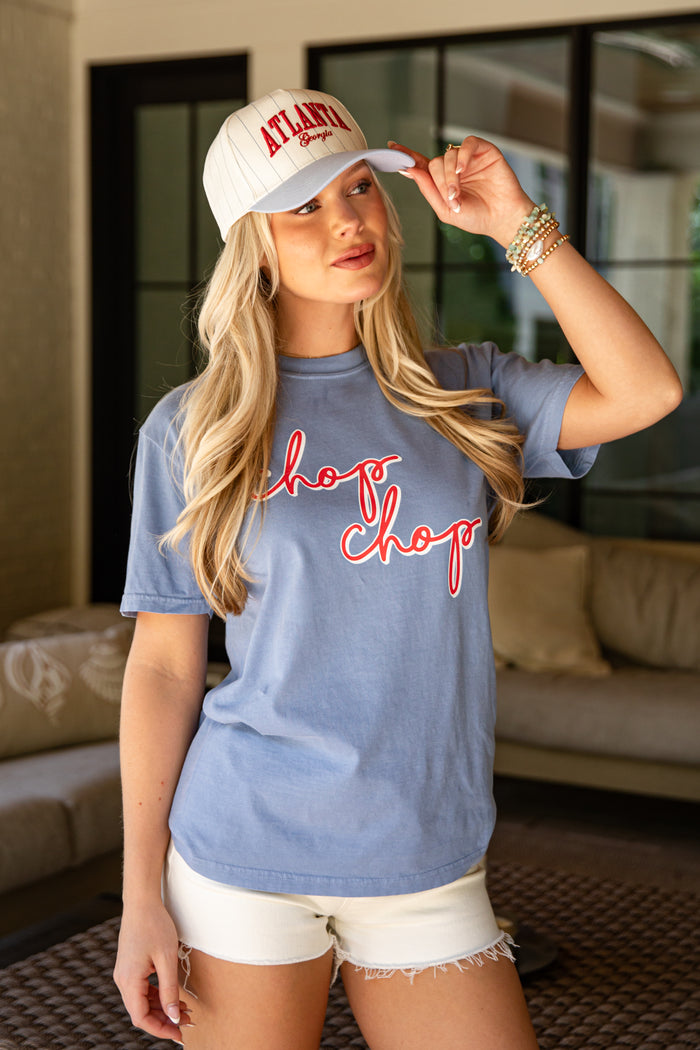 Woman wearing a blue 'Chop Chop' t-shirt and white cap indoors.