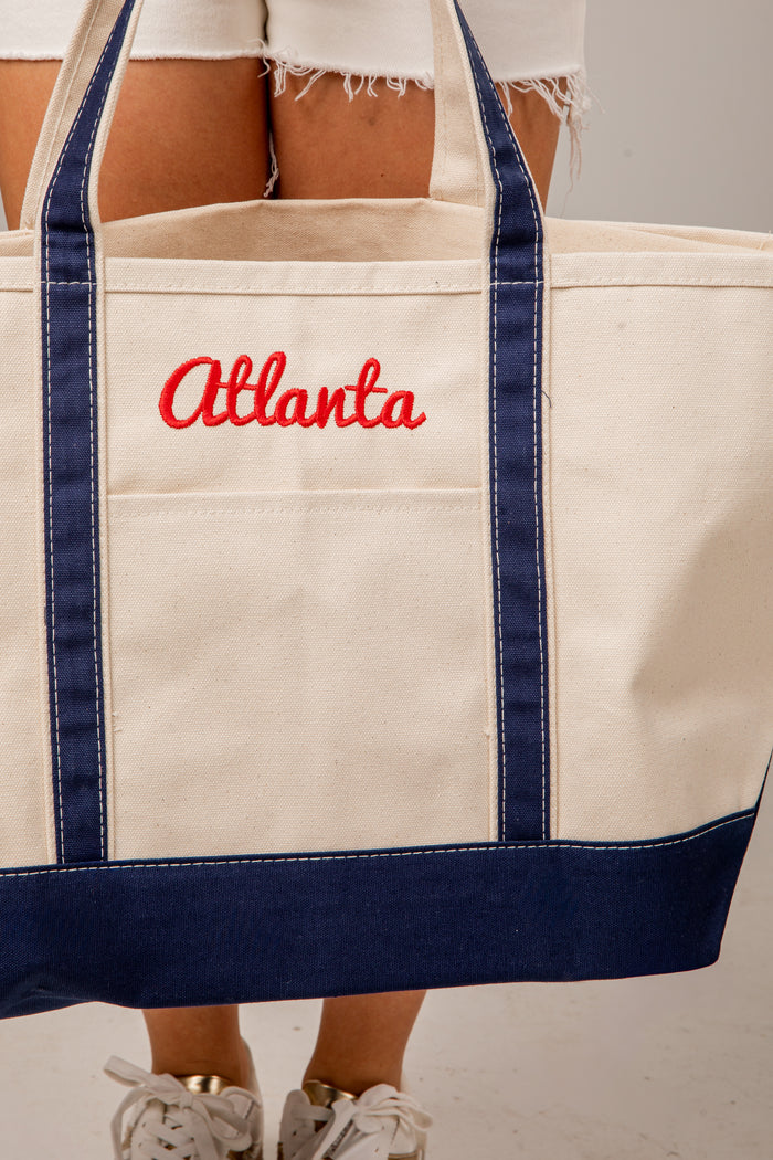 Beige tote bag with 'Atlanta' embroidered in red on a plain background
