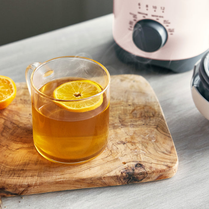 Glass of iced tea with lemon slices on a wooden board, with a pink appliance in the background.
