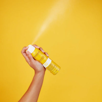 Bioderma Photoderm Invisible Mist SPF50+ 150ml hand spraying into air with yellow background