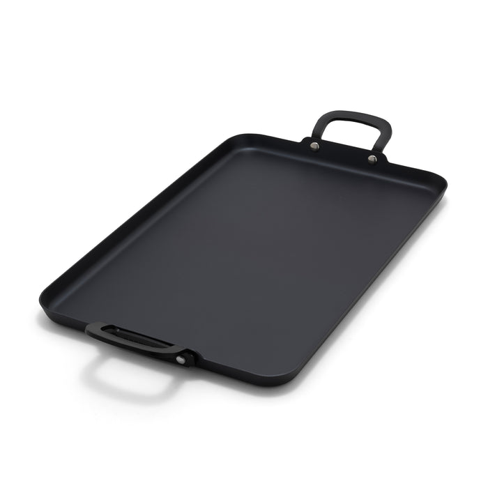 Carbon steel double burner griddle with two handles on a white background.