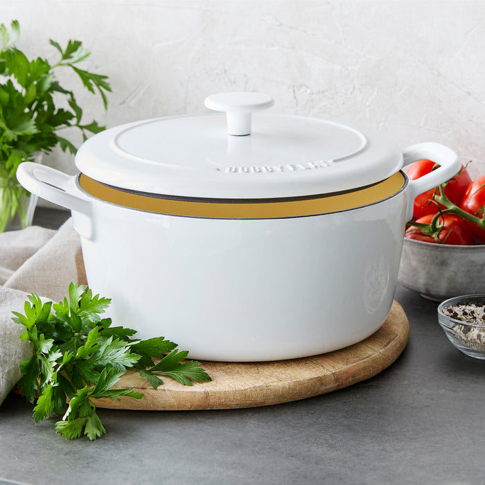 Ivory Dutch oven with lid on a wooden board, surrounded by fresh parsley and tomatoes. 5.5-quart size.