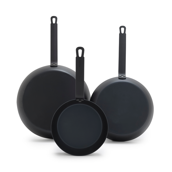 Set of three carbon steel frypans in 8, 10, and 12 sizes, standing upright against a white background.