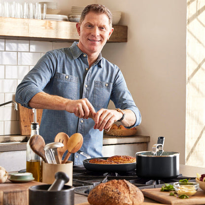Two men cooking with a black ceramic nonstick cookware set on the stove; one wears a denim shirt, both are smiling.