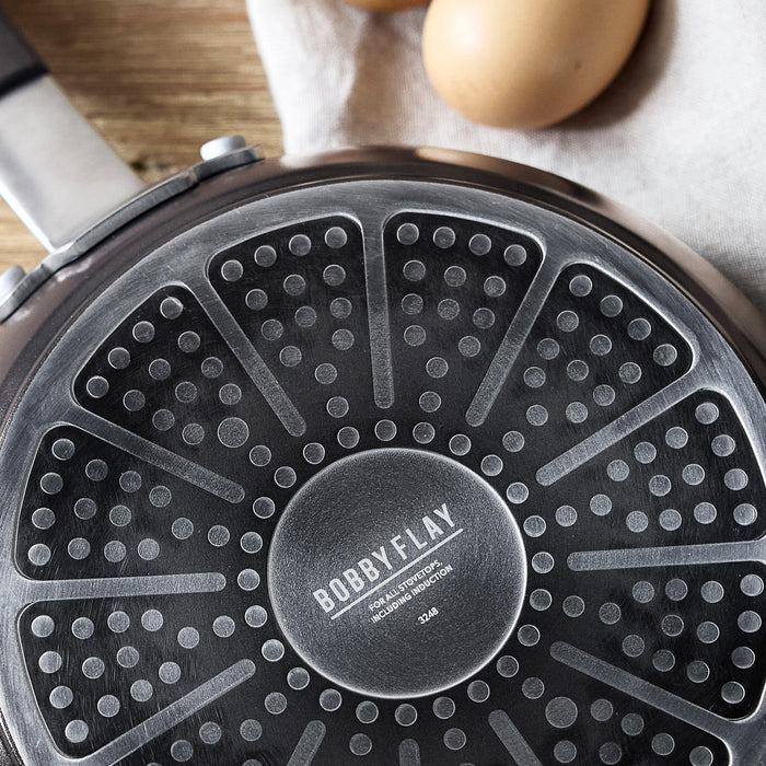 Black ceramic nonstick cookware set with multiple pieces, eggs in the background.