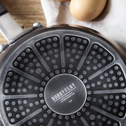 Black ceramic nonstick cookware set with multiple pieces, eggs in the background.
