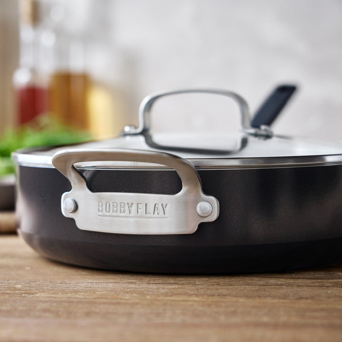 Black ceramic nonstick cookware set on a wooden surface.