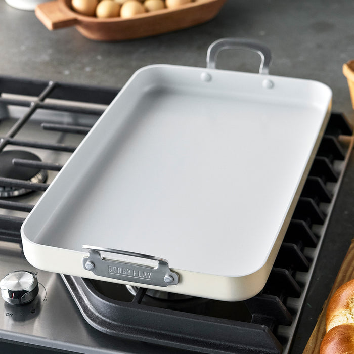 Large rectangular ceramic nonstick griddle on a stovetop in a modern kitchen.