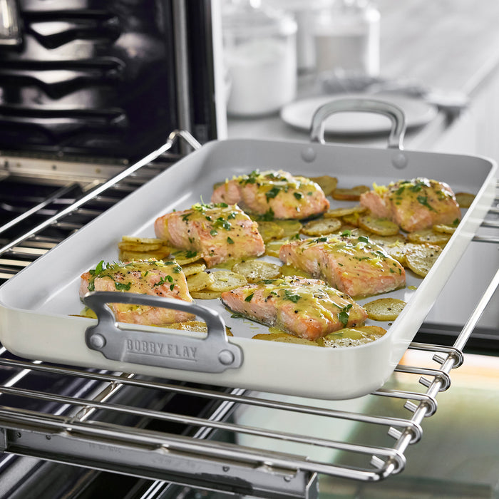 Salmon fillets and potatoes on a ceramic nonstick double burner griddle inside an oven.