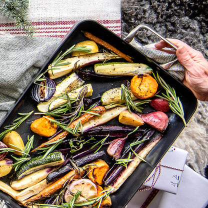 Ceramic nonstick 13.8″ x 10″ rectangular roasting pan filled with roasted root vegetables and fresh rosemary.