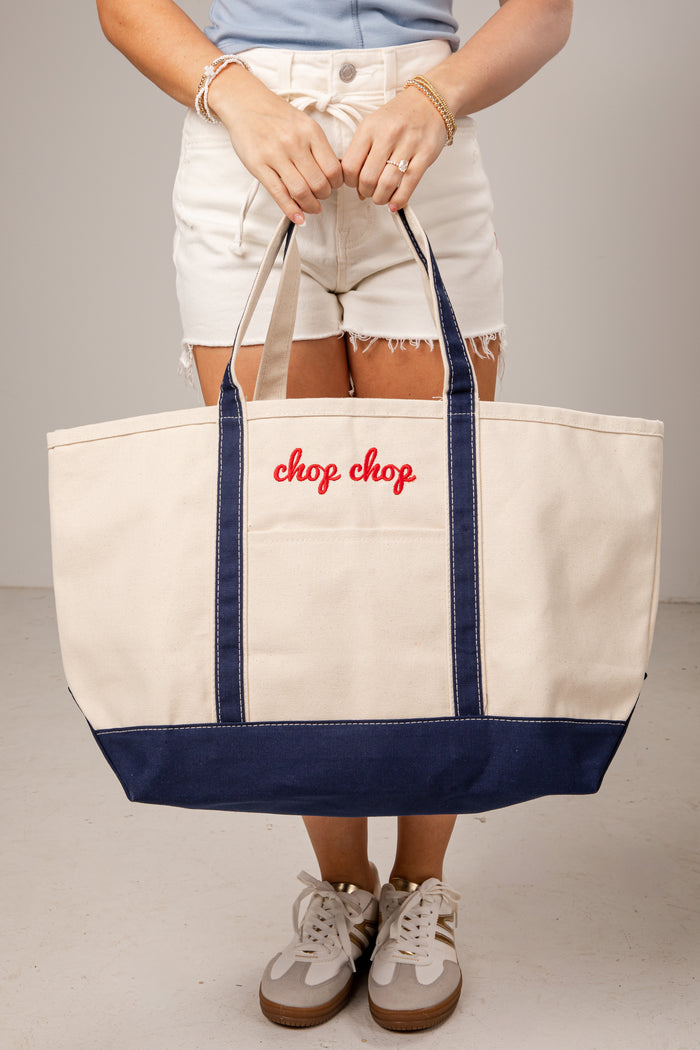 Person holding a tote bag with 'chop chop' text against a neutral background