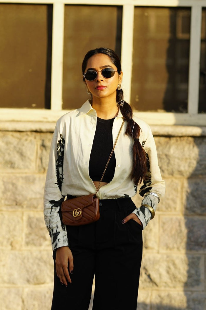 Woman wearing the CM shirt with black trousers, outdoors, front view, hand in pocket