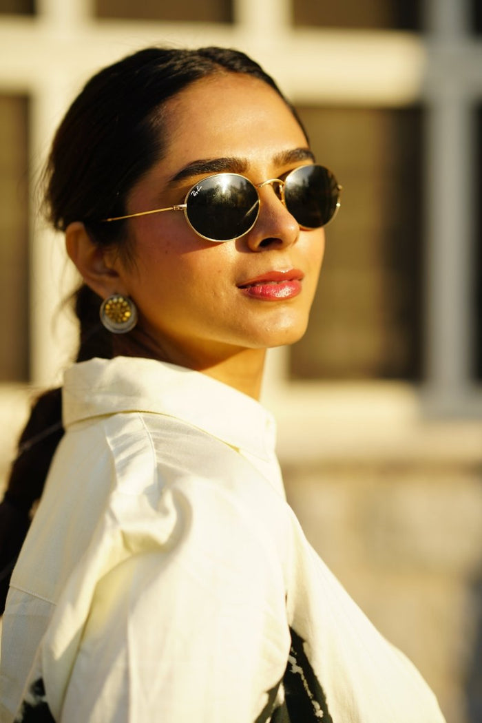 Close view of a woman in sunglasses wearing the white CM shirt collar, outdoors