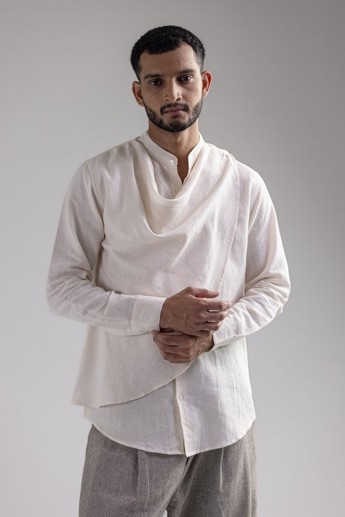 Man wearing the white Cowl shirt with grey trousers, front view, hands held together
