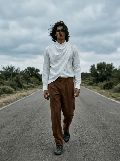 Man wearing the white Cowl shirt with brown trousers, full length front view, walking on an open road
