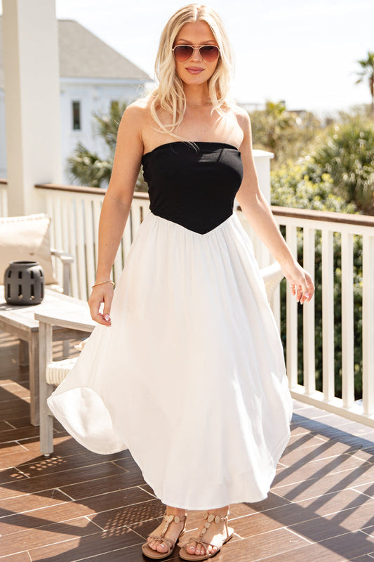 Woman in a black and white dress standing on a patio with a scenic background