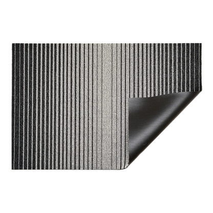 Inspired by the sharp contrast and mesmerizing motion of a cascading row of dominoes, the variegated stripes of this easy-care floor mat are at once dynamic and serene.