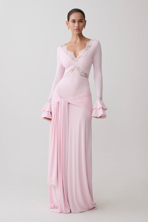 Woman wearing a pink evening gown with long sleeves.