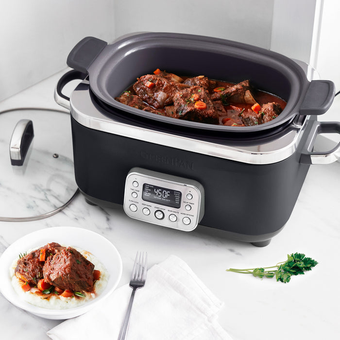 Black slow cooker with digital display on a marble countertop, containing stewed meat and vegetables.