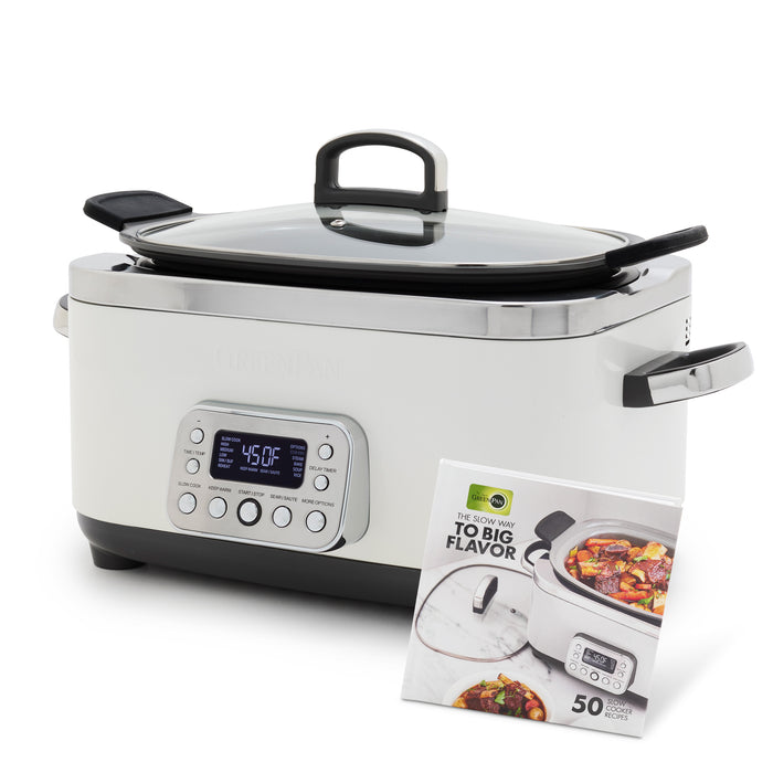The Elite 14-in-1 6-Quart Slow Cooker in Cloud Cream features a digital display, control buttons, glass lid, and side handles. A cookbook and dish of vegetables and meat highlight its easy presets for effortless cooking.