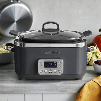 Graphite 14-in-1 slow cooker on a kitchen counter, with food inside and a yellow towel nearby.