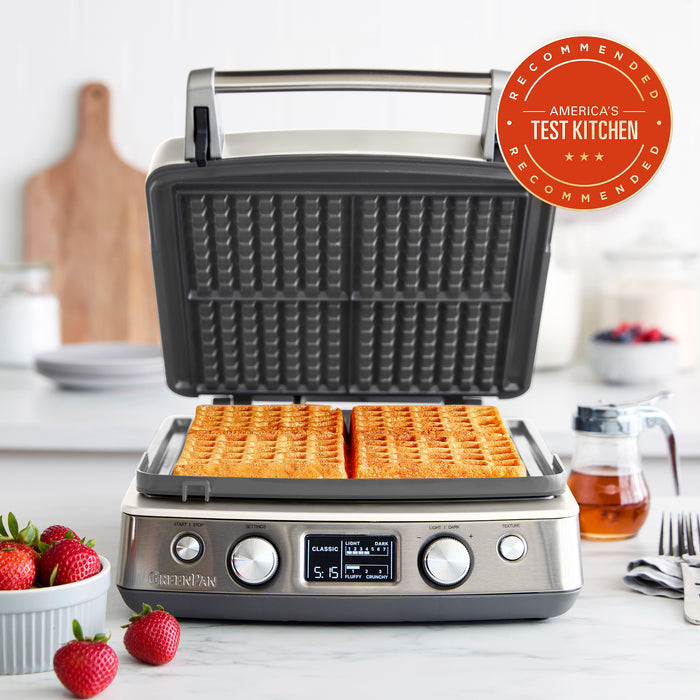 Cloud cream ceramic 4-square waffle maker on a kitchen counter with fresh waffles and strawberries.