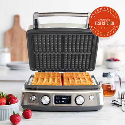 Cloud cream ceramic 4-square waffle maker on a kitchen counter with fresh waffles and strawberries.