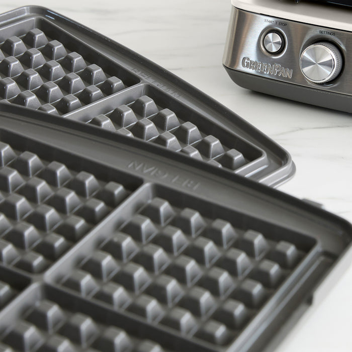 White ceramic 4-square waffle maker with silver control knobs and removable nonstick plates for Belgian waffles.