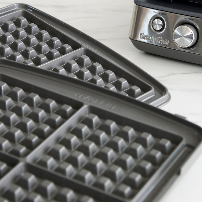 Ceramic 4-square waffle maker plates on a white countertop, shown up close.
