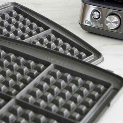Ceramic 4-square waffle maker plates on a white countertop, shown up close.