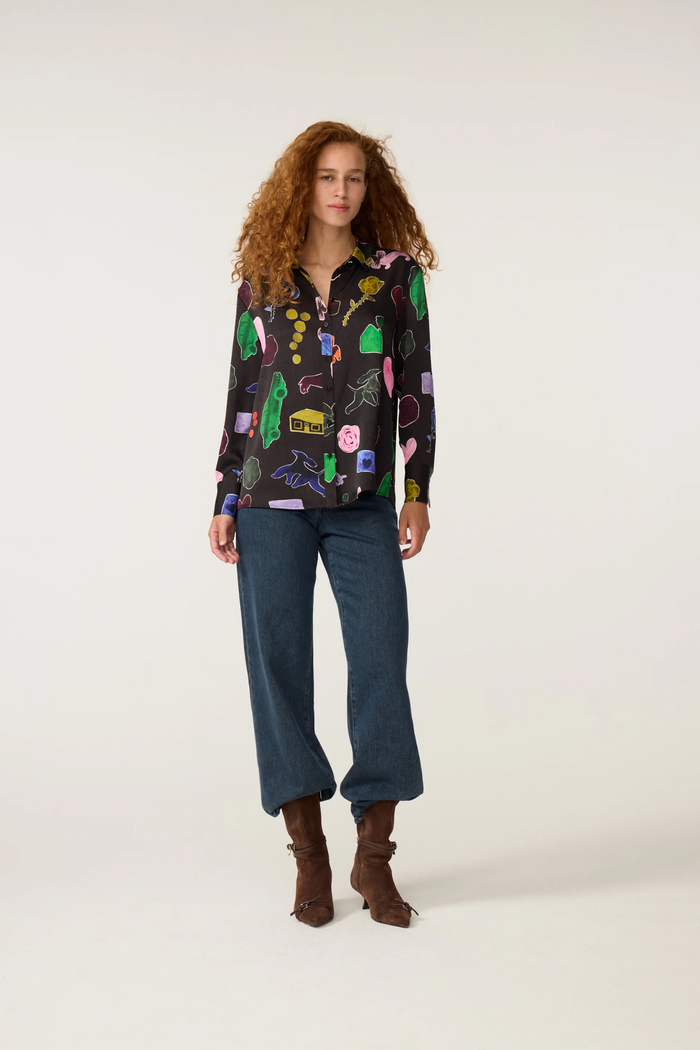 Woman wearing a colorful printed blouse with dark jeans and brown boots Dotique fashion style