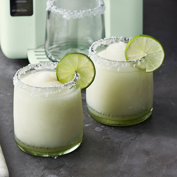 Frost Classic Ice Cream  Frozen Drink Recipe Book with two lime-garnished frozen cocktails on a gray surface.