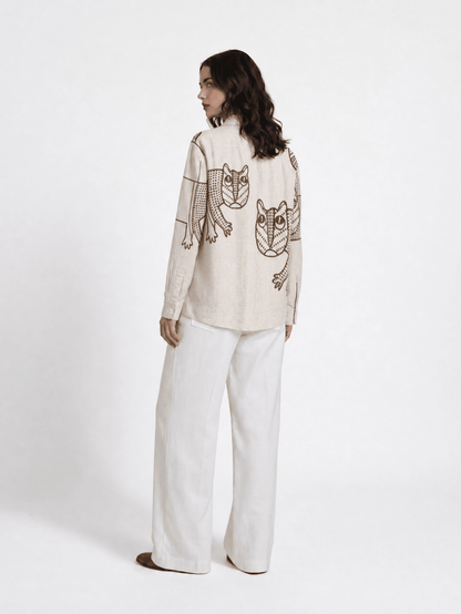 Woman wearing the off white Gond Tiger shirt with white trousers, full length back view, looking over her shoulder