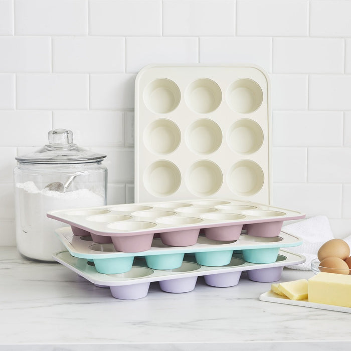 Navy ceramic nonstick muffin pan on a kitchen counter with flour and baking ingredients nearby.