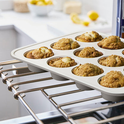 Ceramic nonstick muffin pan in quartz gray holding muffins on an oven rack in a bright kitchen.