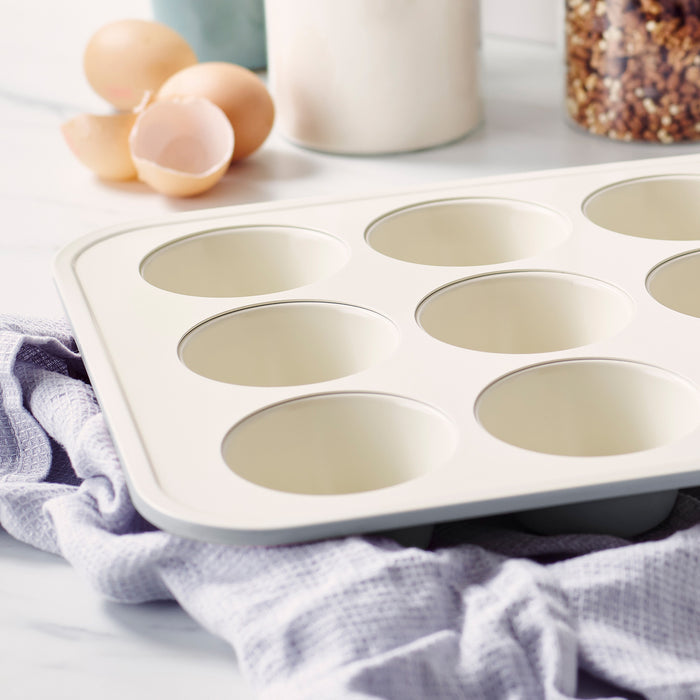 Quartz gray ceramic muffin pan on a kitchen counter with towel, eggshells, and glass jars nearby.