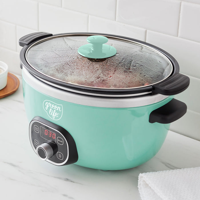 Turquoise slow cooker with a glass lid on a kitchen counter.