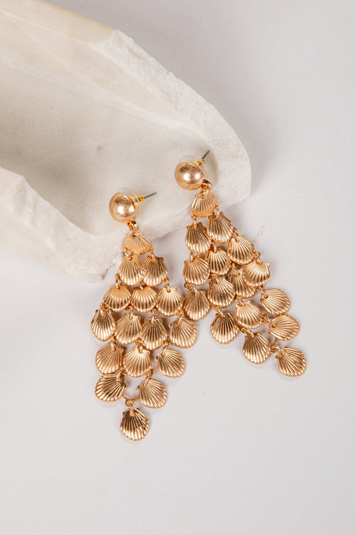 Gold chandelier earrings on a white fabric background