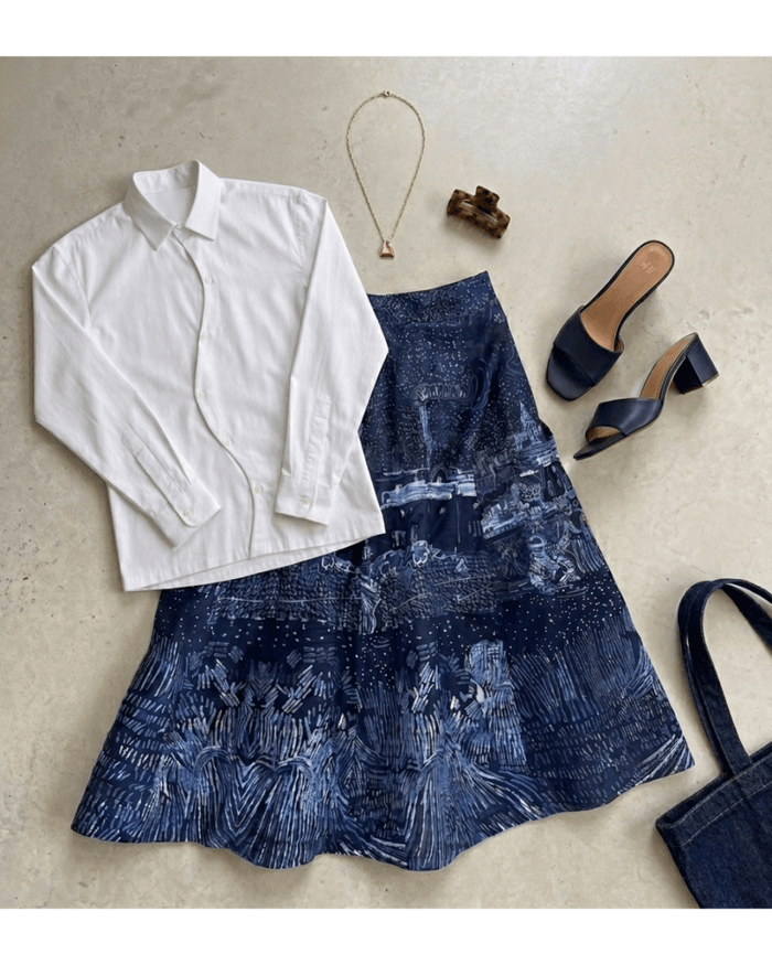 Harvest skirt for women in blue cotton, laid flat with a white shirt, blue sandals, a necklace and a bag
