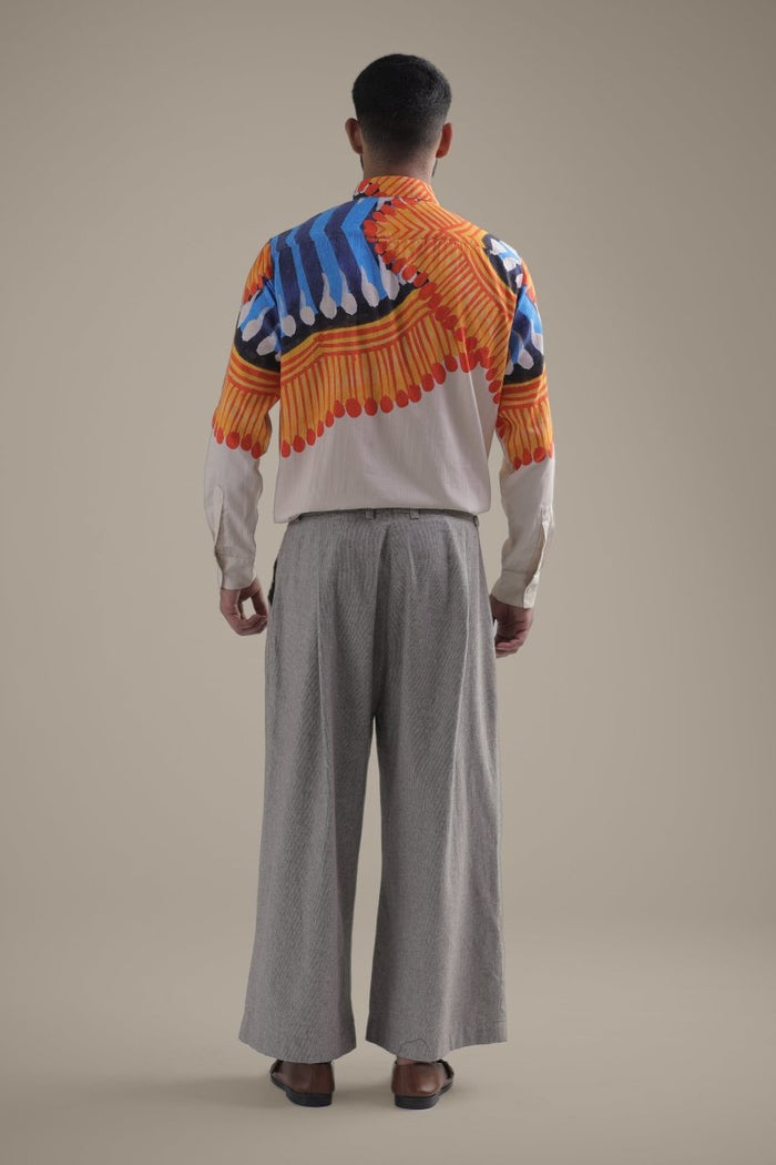 Man wearing the Kalighat Fire shirt with wide grey trousers, full length back view, orange and blue strokes on the shoulders