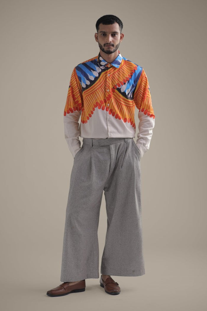 Man wearing the Kalighat Fire shirt with wide grey trousers, full length front view, hands in pockets