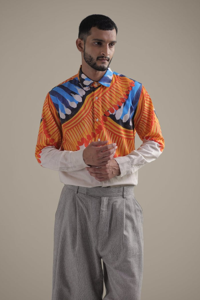 Man wearing the Kalighat Fire shirt with grey trousers, waist-up three-quarter view, hands clasped