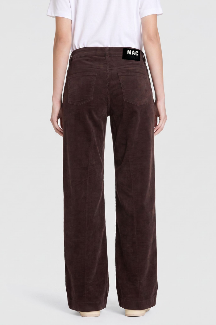 Back view of a model wearing brown wide leg trousers with a visible MAC waistband label