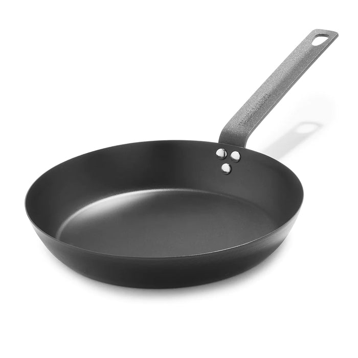 Carbon steel 10-inch frypan with a seasoned patina and long metal handle on a white background.