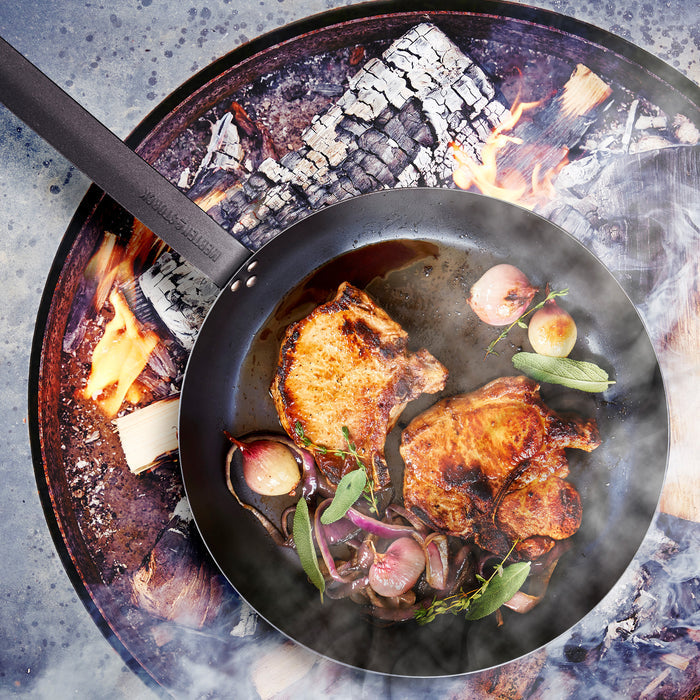 Pork chops with onions and herbs cooking in a Merten  Storck 8-inch carbon steel frypan over a wood fire.