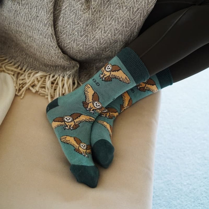 Bamboo socks with barn owl pattern worn by a person sitting on a couch.