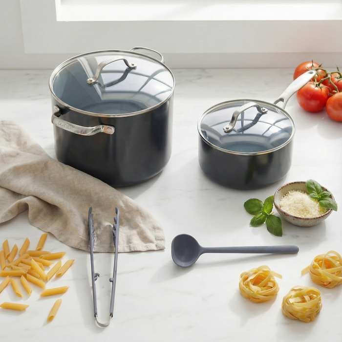 Pasta Night Bundle with pasta, utensils, tomatoes, basil, cheese, and a skillet on a white countertop.